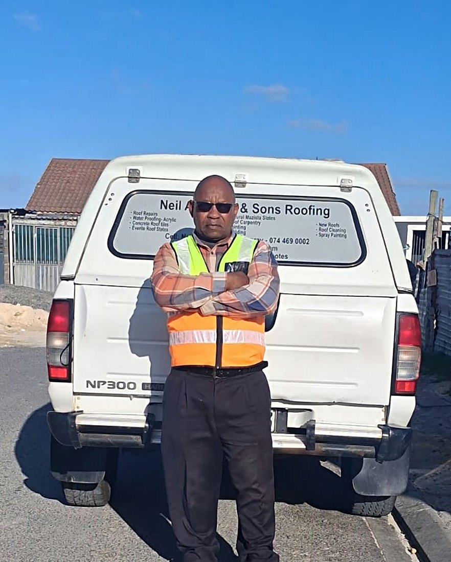 Neil Ambrose standing in front of his roofing bakkie