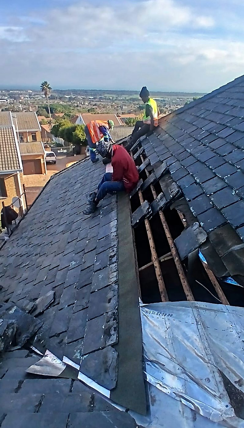 Roofers replacing damaged slates and flashing on a steep slate roof